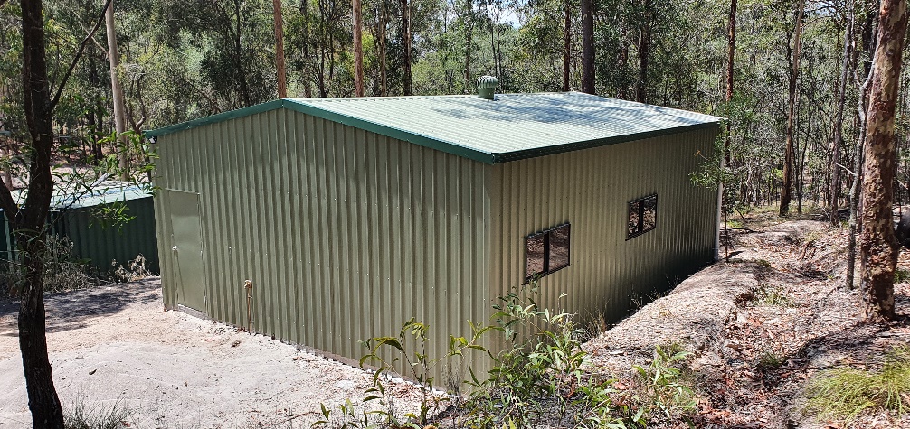 A green building in the woodsDescription automatically generated